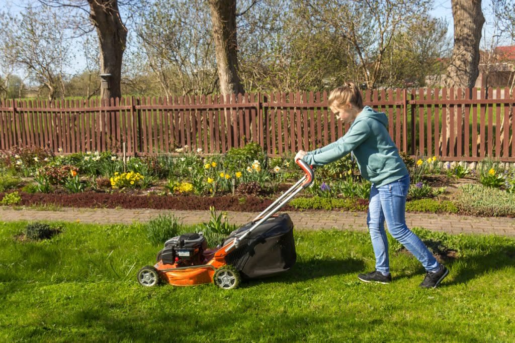 A teenager mows a lawn.