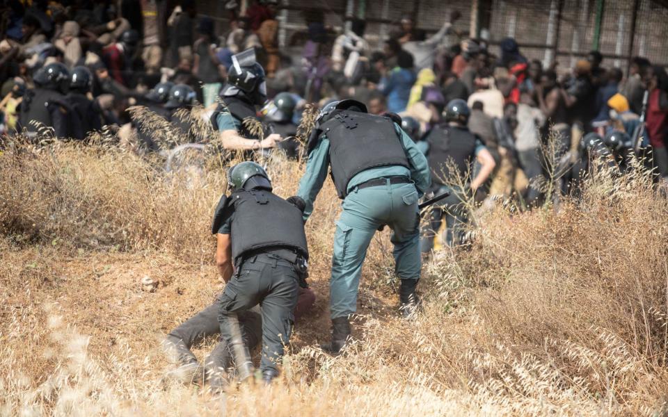 Guards confront a migrant on the ground - Javier Bernardo/AP