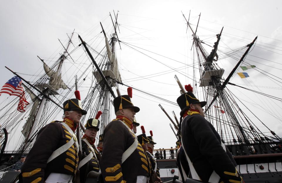 Military reenactors in the uniforms of U.S. Marines from the war of 1812 march in front of the USS Constitution moments after the vessel arrived at her berth in Charlestown Navy Yard, in Boston, Sunday, Aug. 19, 2012. The U.S. Navy's oldest commissioned war ship sailed under her own power Sunday for the first time since 1997. The sail was held to commemorate the 200th anniversary of the ship's victory over HMS Guerriere in the War of 1812. (AP Photo/Steven Senne)