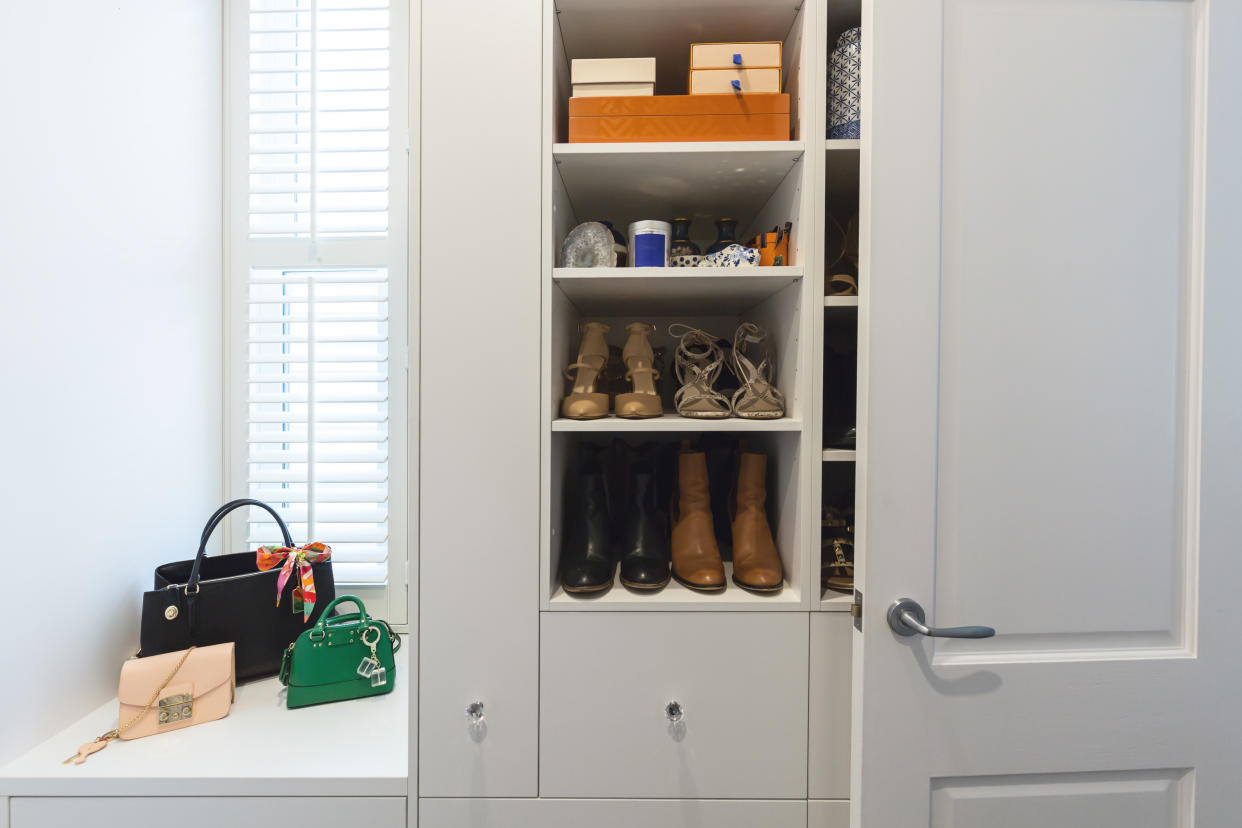 A small closet with shoes on a shelf. 