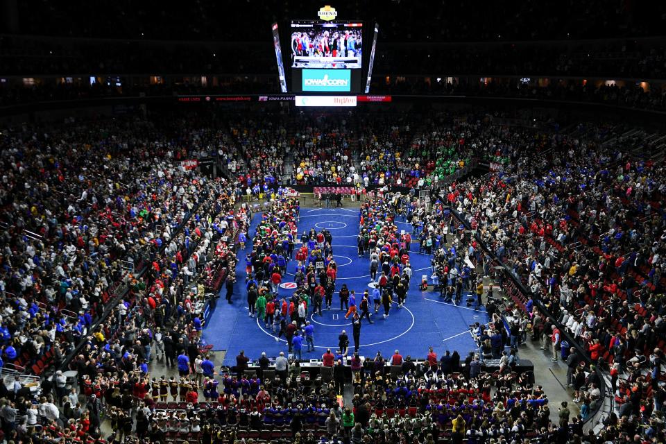 Spectators stand as the grand march of Iowa High School State Wrestling Tournament medal winners enter Wells Fargo Arena before the championship rounds of the tournament on Saturday, Feb. 21, 2022, in Des Moines.