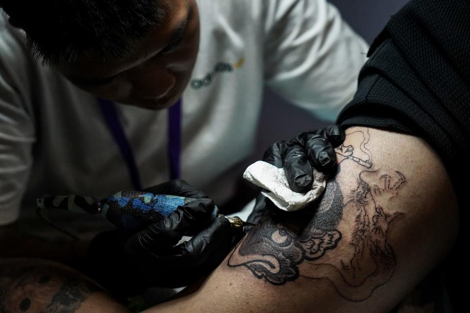 A participant gets a tattoo by a tattoo artist at the Land of ink Bangkok Tattoo Convention