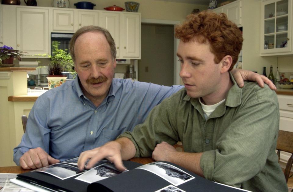 Tim Kahn sits in South Burlington in 2003 with his son, Ben Kahn, as they look through photos from France. Ben Kahn made a documentary film, "The Last Link," which was shown at Shelburne Farms.