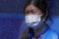 A masked worker walks by a rain-covered window after a rain storm at a field hockey match at the 2020 Summer Olympics, Tuesday, July 27, 2021, in Tokyo, Japan. (AP Photo/John Locher)