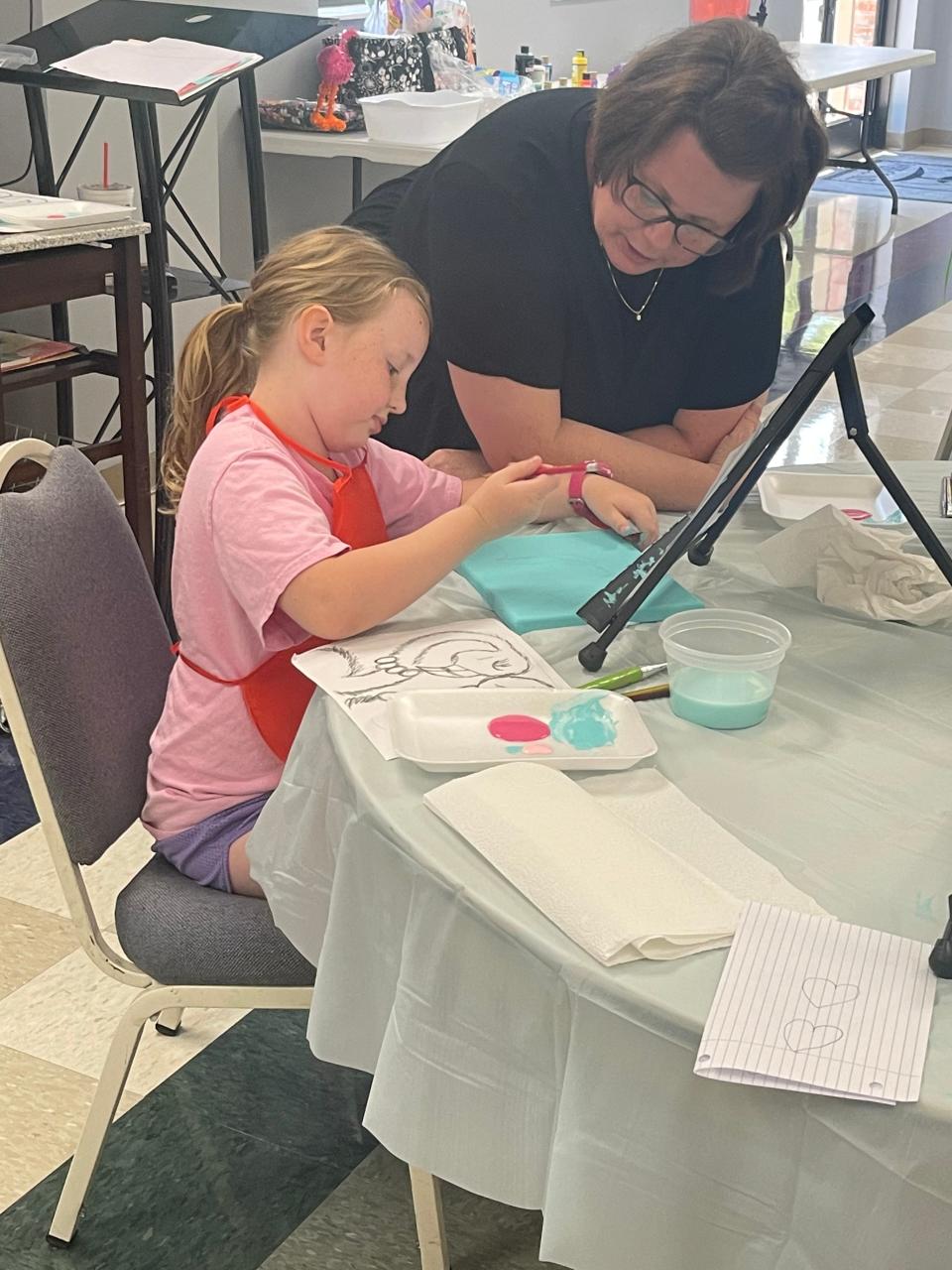 Charisma Stinnett works with a student in her summer art class.