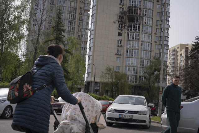 People pass by an apartment building damaged by a drone that was shot down, during a Russian overnight strike, amid Russia's attack, in Kyiv, Ukraine, Monday, May 8, 2023. (AP Photo/Andrew Kravchenko)