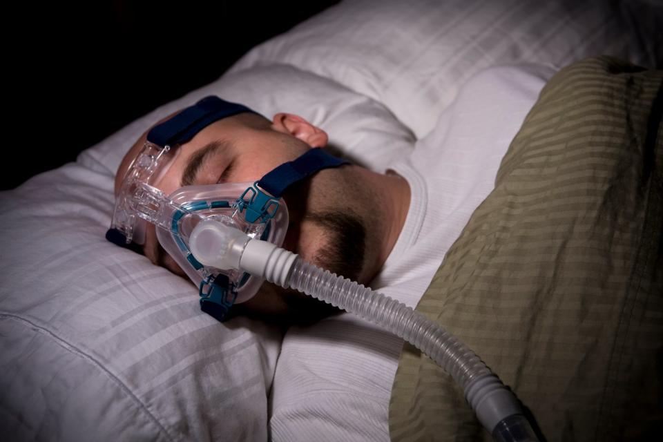 A person sleeping with a CPAP machine.