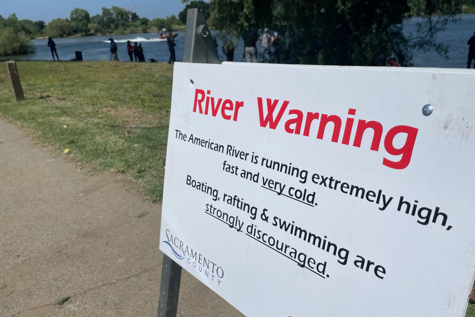 A sign warning the public of dangerous river conditions is posted alongside the American River in Sacramento, Calif., Tuesday, May 23, 2023. California rivers fed by winter's massive Sierra Nevada snowpack have been turned into deadly torrents, drawing warnings from public safety officials ahead of the Memorial Day weekend and the traditional start of outdoor summer recreation. (AP Photo/Haven Daley)