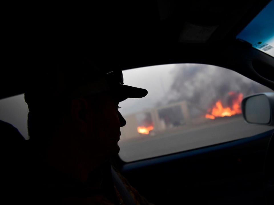 A person in silhouette observes the Colorado fires from their car.