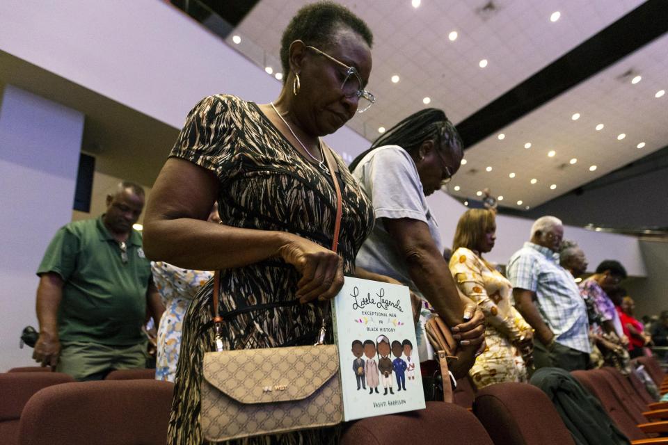 Linda Mobley hangs her head in prayer as she holds a book that could be banned under the state's newly adopted curriculum standards on African-American history, during an education town hall regarding the state's newly adopted curriculum standards on African-American history at Antioch Missionary Baptist Church, Thursday, Aug. 10, 2023 in Miami Gardens, Fla. (D.A. Varela/Miami Herald via AP)