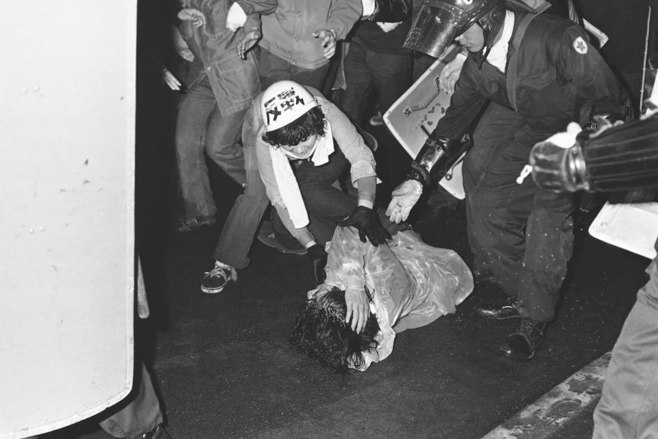 FILE - A participant in anti-war demonstration against the presence of U.S. military bases on Okinawa island helps her friend who fell on the ground after a scuffle with riot police in Tokyo on May 15, 1972. Okinawa on Sunday, May 15, 2022, marks the 50th anniversary of its return to Japan on May 15, 1972, which ended 27 years of U.S. rule after one of the bloodiest battles of World War II was fought on the southern Japanese island. (AP Photo/Sadayuki Mikami, File)