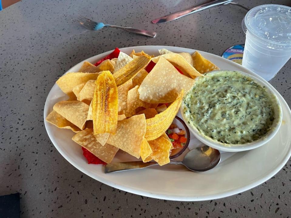 Spinach and artichoke dip in small bowl next to pile of chips at Bahama Breeze