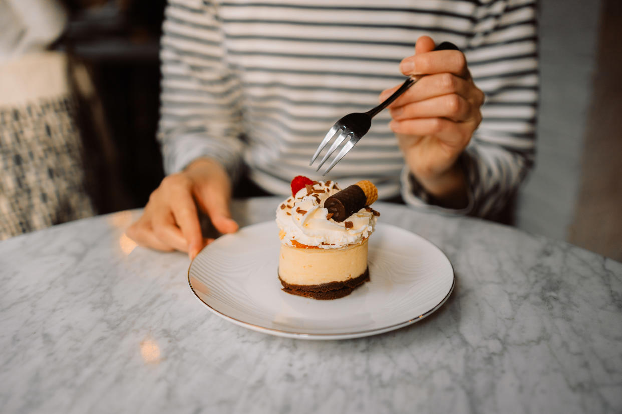 Close up image of a beautiful woman eating chocolate cake at cafe. High quality photo