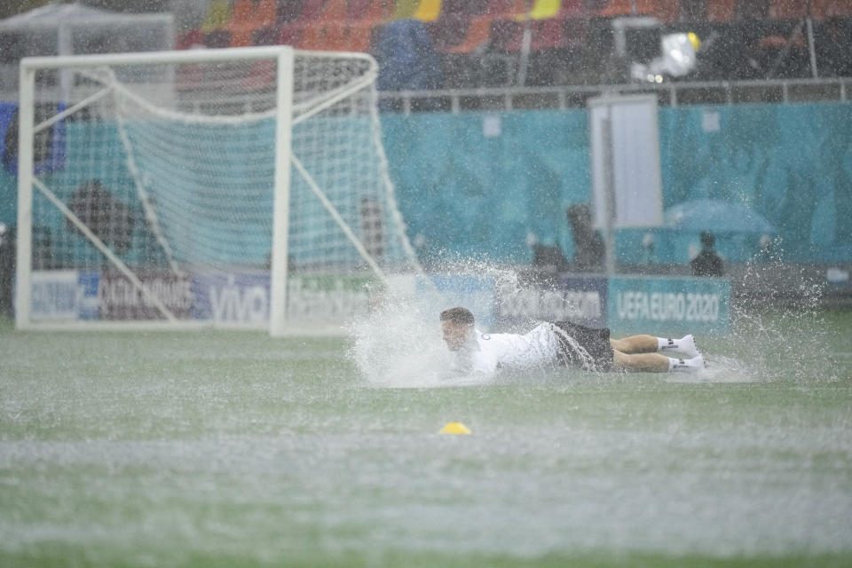 Austria's Christoph Baumgartner takes a dive on the pitch during a heavy rainfall before a training session at the National Arena stadium in Bucharest, Romania, Saturday, June 12, 2021, the day before the team's first match against North Macedonia. (AP Photo/Vadim Ghirda)