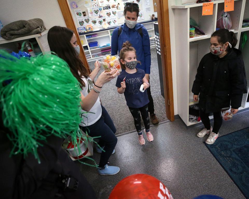 Vivian Gray, 5, gives a couple of celebratory hops after taking a sucker from kindergarten teacher Natasha Heino as she and her mother, Jennifer, exit after Vivian received her COVID-19 vaccination at Silverwood School on Thursday.