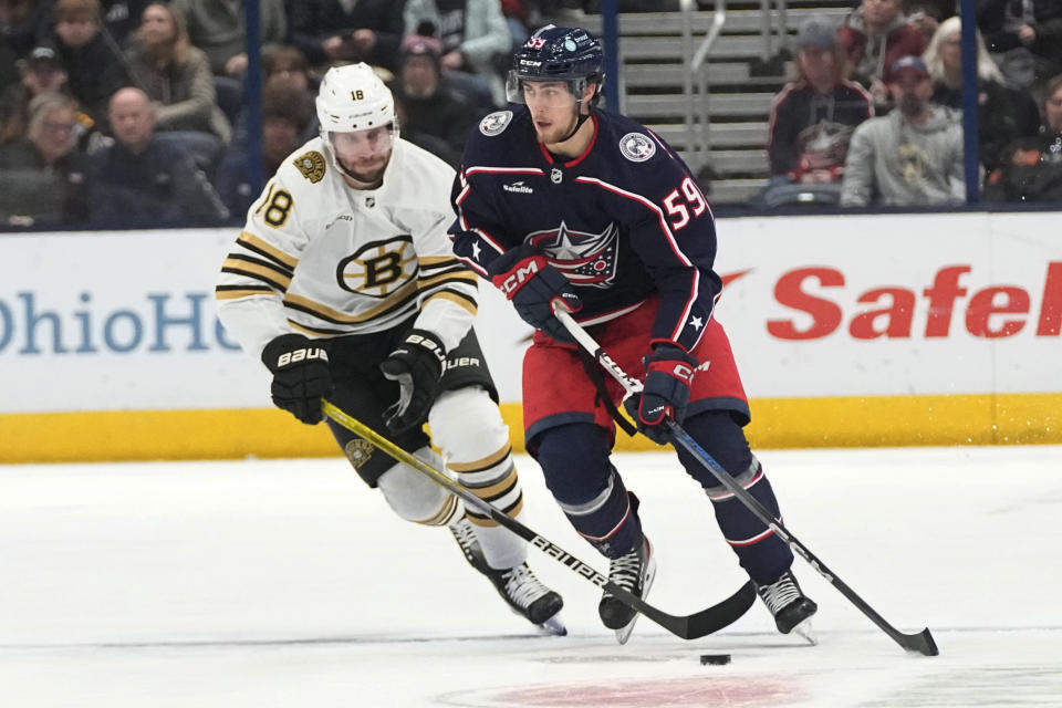 Columbus Blue Jackets right wing Yegor Chinakhov (59) is pursued by Boston Bruins center Pavel Zacha (18) in the second period of an NHL hockey game Tuesday, Jan. 2, 2024, in Columbus, Ohio. (AP Photo/Sue Ogrocki)