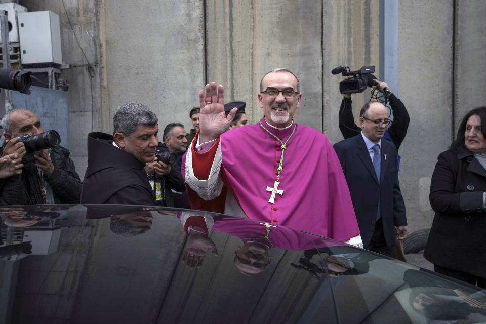 Latin Patriarch Pierbattista Pizzaballa greets worshippers next to the separation wall between the West Bank city of Bethlehem and Jerusalem on his way to the Church of the Nativity, traditionally believed to be the birthplace of Jesus Christ, in the West Bank town of Bethlehem during Christmas, Saturday , Dec. 24, 2022. (AP Photo/Mahmoud Illean)