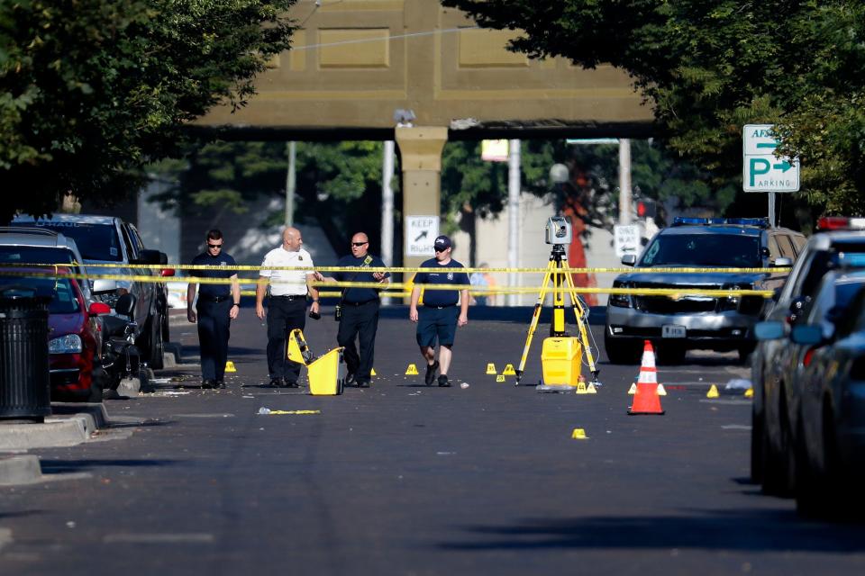 Authorities walk among evidence markers at the scene of a mass shooting, Sunday in Dayton, Ohio. Nine people were killed in the second mass shooting in the U.S. in less than 24 hours, and the suspected shooter is also deceased, police said.