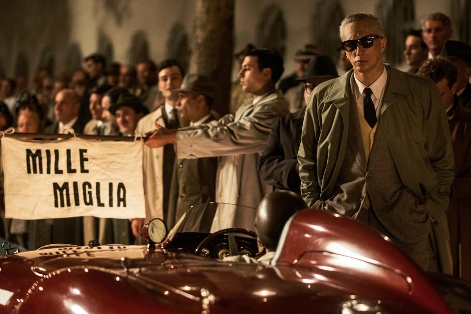 Adam Driver, as Enzo Ferrari, stands near a car preparing to depart for the Mille Miglia race in this still from "Ferrari."