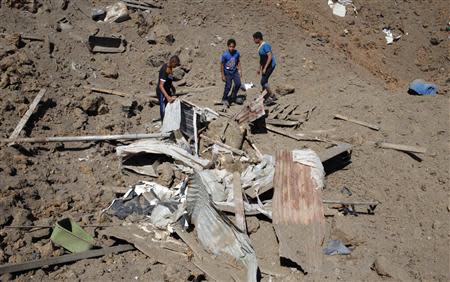 Palestinians inspect the scene of an Israeli air strike in the central Gaza Strip April 21, 2014. REUTERS/Ibraheem Abu Mustafa
