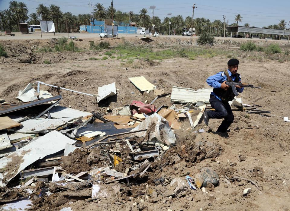 An Iraqi policeman stands guard at the site of a car bomb explosion in Hillah, about 60 miles (95 kilometers) south of Baghdad, Iraq, Thursday, April 24, 2014. A suicide bomber rammed his explosives-laden car into a police checkpoint south of Baghdad on Thursday morning, killing several people, officials said, the latest episode in an uptick in violence in the run-up to next week's parliamentary elections. (AP Photo/Karim Kadim)