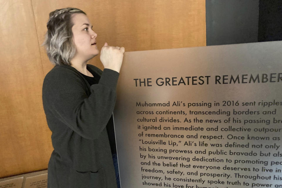 Bess Goldy, curator of a new exhibit at the Muhammad Ali Center in Louisville, Ky., holds a display recounting the days after Ali's death in 2016. Workers put the exhibit together on Thursday, April 4, 2024, ahead of its opening to the public. (AP Photo/Bruce Schreiner)