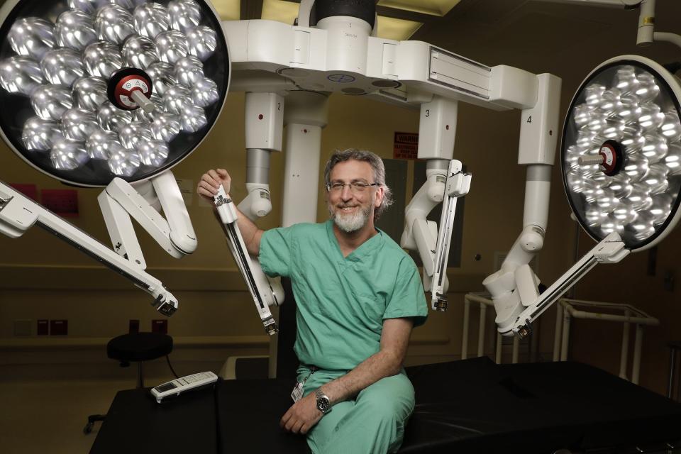 Dr. Ron Landmann, the surgeon who heads the Baptist MD Anderson Cancer Center's colorectal surgery division in Jacksonville, shows one of the operating rooms with the da Vinci robotic surgical system. This portion of the da Vinci system has four remotely controlled arms that hold the surgical devices that work on the patient in the operating room.