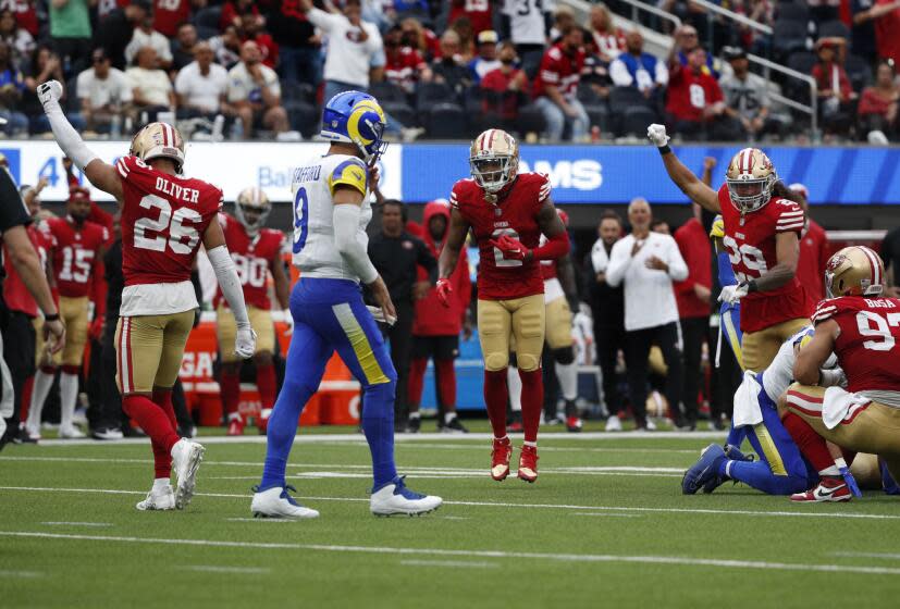 The 49ers celebrate a fourth-down stop of the Rams as quarterback Matthew Stafford walks away.