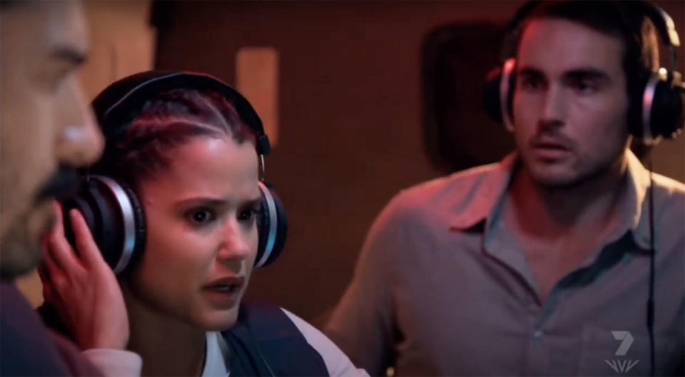 Rose is listening through headphones as Cash stares at her stunned