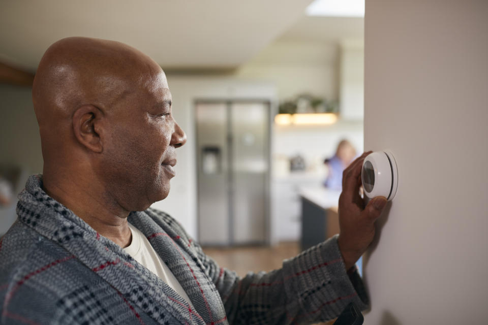 Man adjusting the thermostat in his home