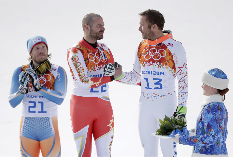 Men's super-G joint bronze medal winners Canada's Jan Hudec and United States' Bode Miller shake hands on the podium as gold medal winner Norway's Kjetil Jansrud stands at left during a flower ceremony at the Sochi 2014 Winter Olympics, Sunday, Feb. 16, 2014, in Krasnaya Polyana, Russia.(AP Photo/Charlie Riedel)