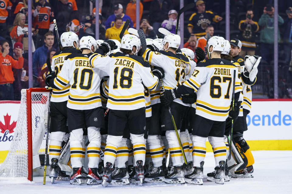 Boston Bruins gather around Jeremy Swayman as they celebrates the win following the third period of an NHL hockey game against the Philadelphia Flyers, Sunday, April 9, 2023, in Philadelphia. The Bruins won 5-3.(AP Photo/Chris Szagola)