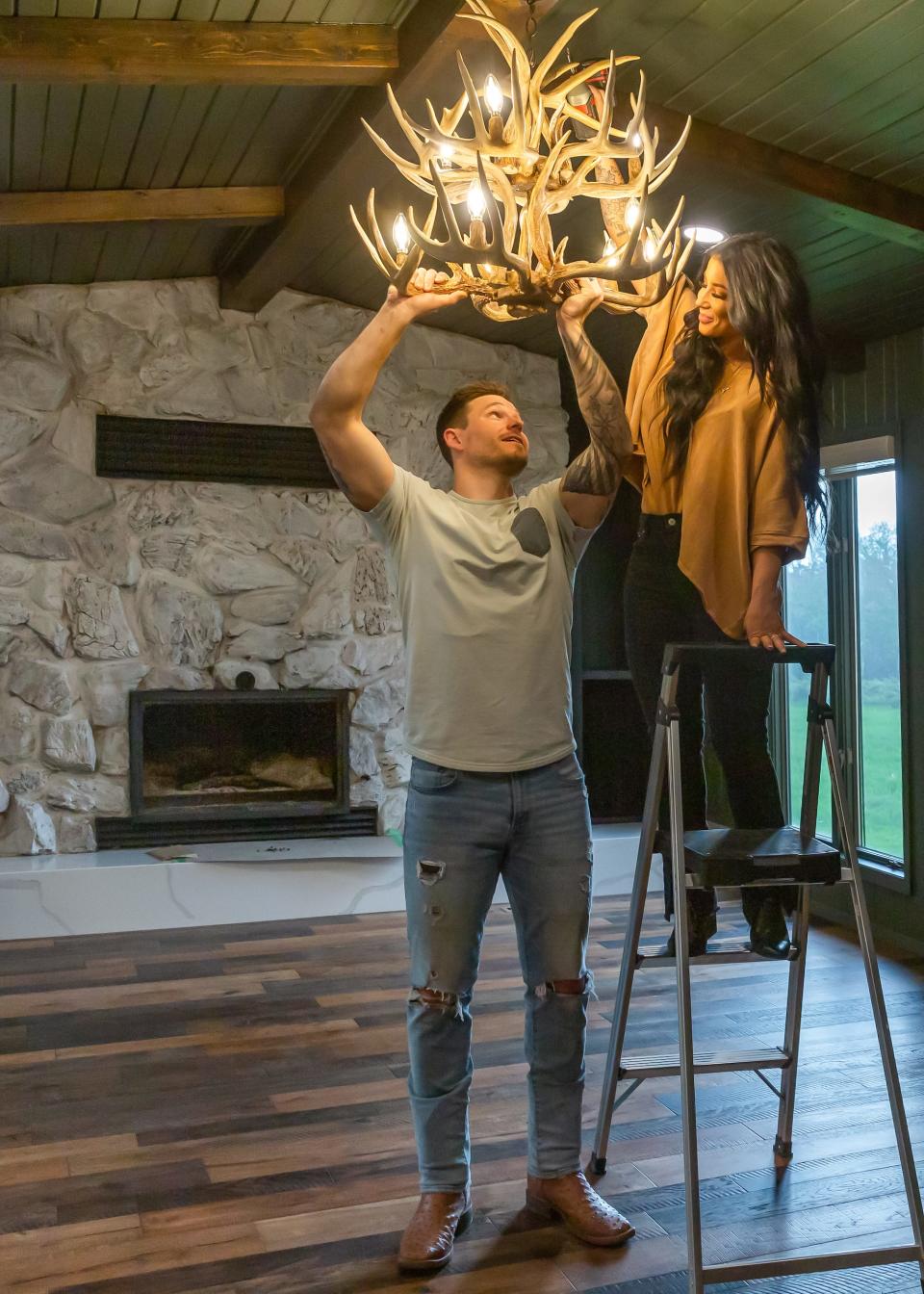 Cole and Chelsea DeBoer hang a chandelier in a home they renovated.