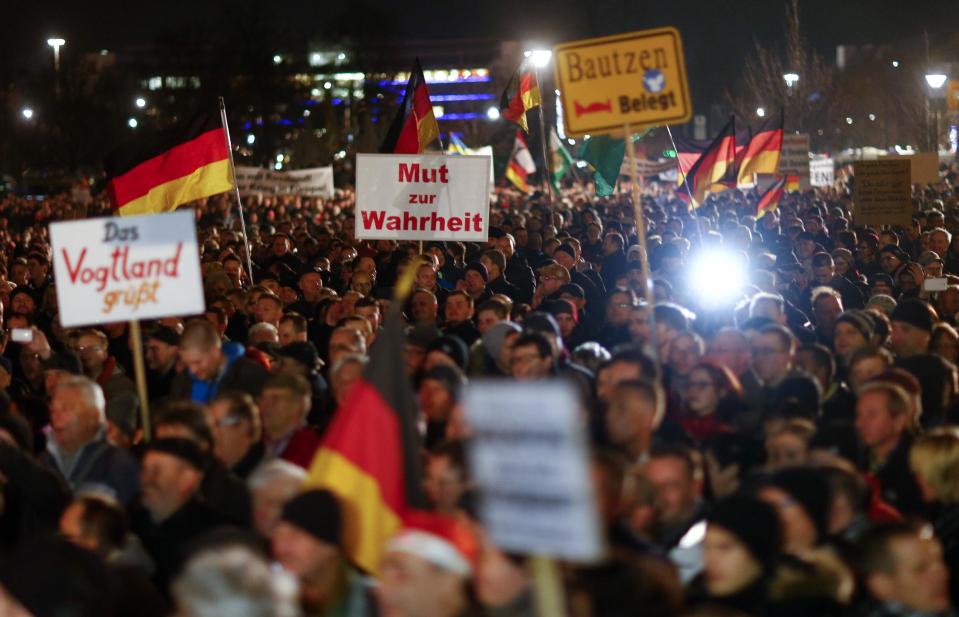 Participants hold banners German national flags during a demonstration called by anti-immigration group PEGIDA in Dresden