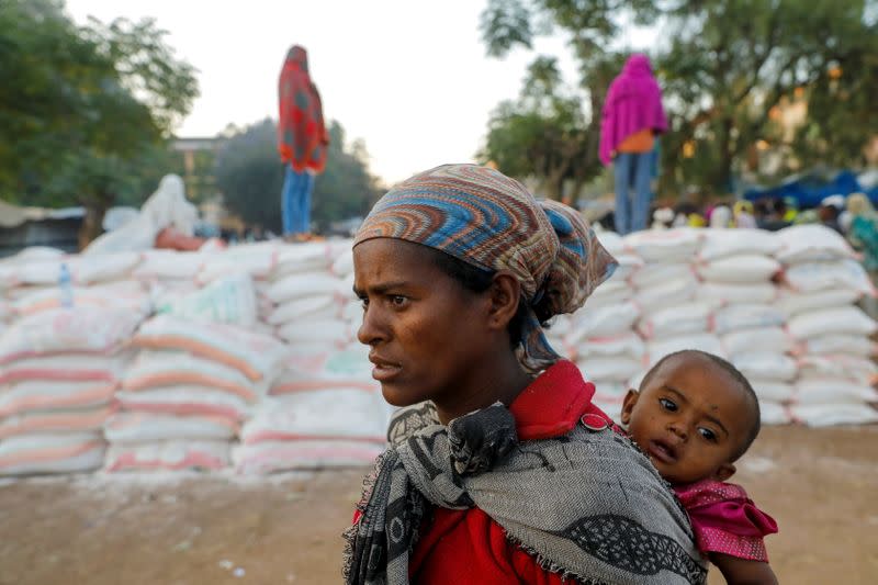 FILE PHOTO: Woman carries an infant as she queues in line for food, at the Tsehaye primary school, in Shire