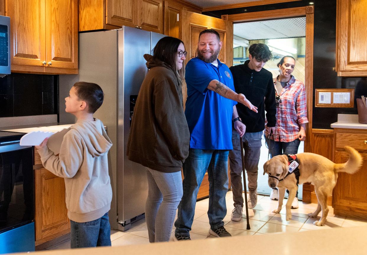 Army veteran Michael Hulsey, center, along with his children Wyatt, 7, Elizabeth, 17, Austin, 18, and his wife, Meaghan, take a closer look at their new kitchen for the first time Saturday, March 19, 2022, in Goldfield. The Hulsey family were given a mortgage-free house donated by Wells Fargo to the Military Warriors Support Foundation.