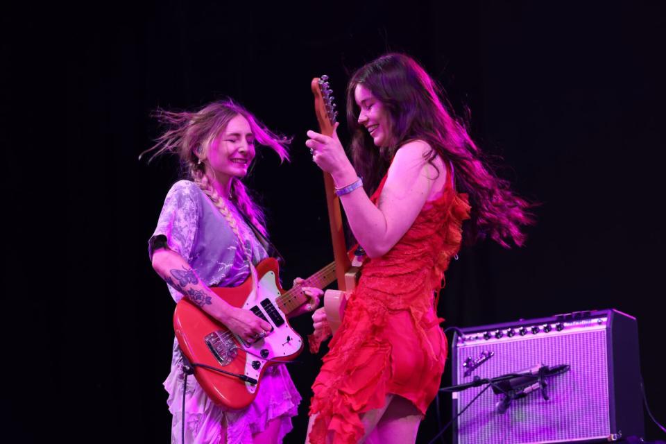 Two female rock musicians perform onstage.