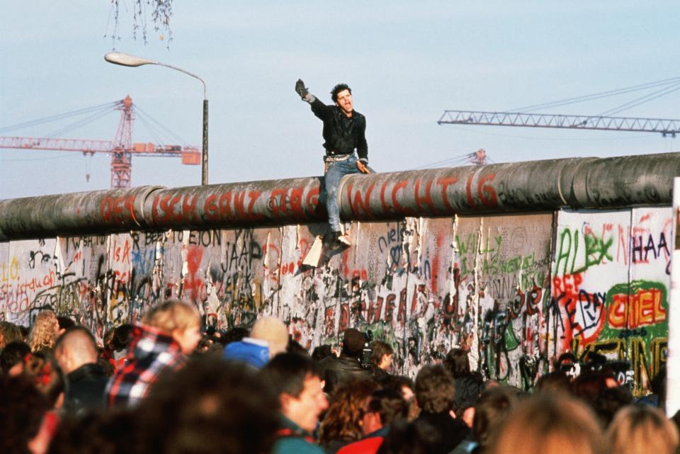 12/11/1989- A German youth waves victoriously from the top of the Berlin Wall after the fall of communism in Germany. Picture- Corbis Images