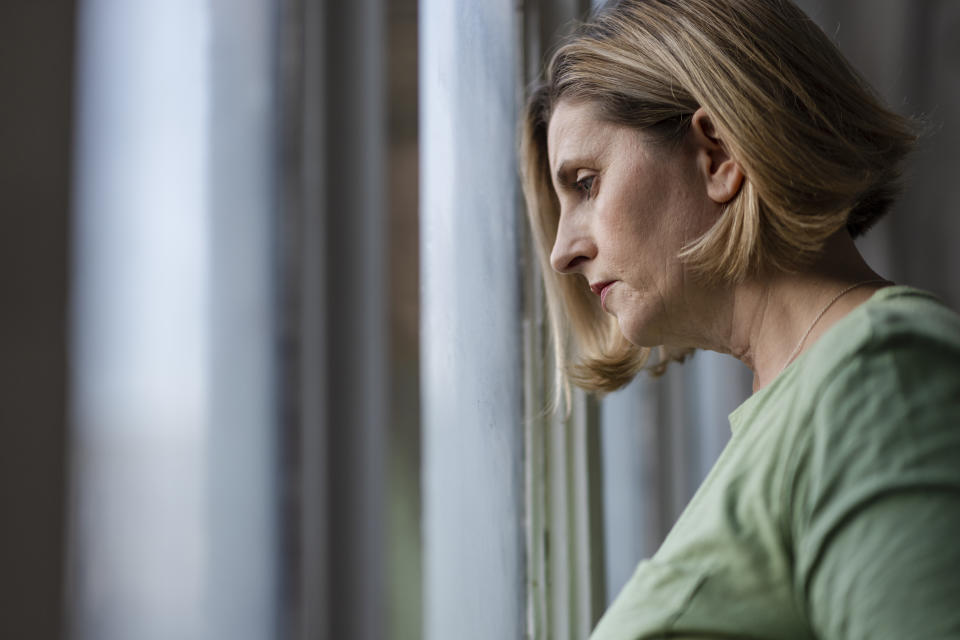 Woman looking out window, serious face