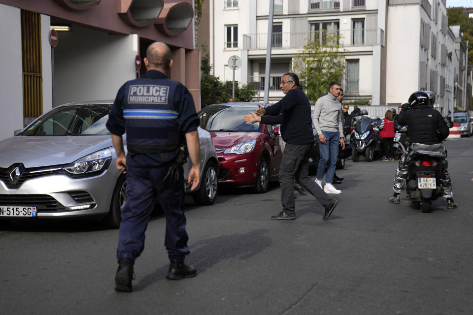 A police officer walks towards an angry driver queuing for fuel Wednesday, Oct. 12, 2022 in Cachan, outside Paris. The French government on Wednesday started the process of requisitioning workers at petrol depots of ExxonMobil's French branch Esso in an attempt to ensure that service stations around the country are supplied with badly needed fuel amid an ongoing strike, saying shortages are becoming "unbearable" to too many in the country.(AP Photo/Francois Mori)