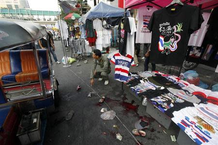 A policeman points at the crime scene following an a bomb blast in Bangkok February 23, 2014. REUTERS/Paul Barker