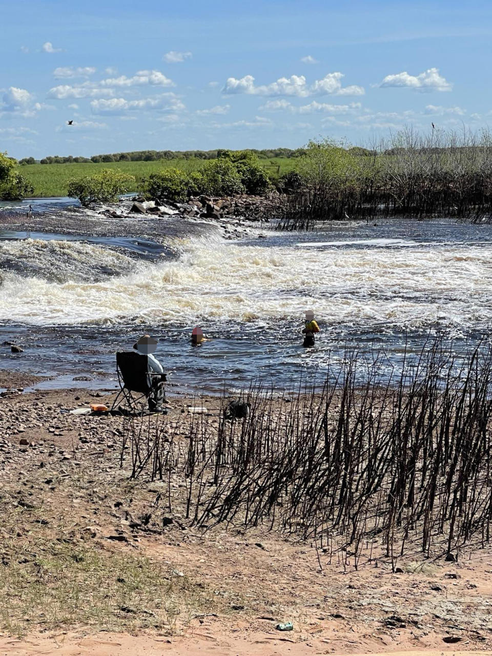 The kids swimming in the crocodile-infested Mary River at the Shady Camp barrage wall and camp ground on Saturday as their dad watches on.