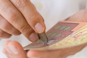 ANMT0Y Man scratching lottery card with coin