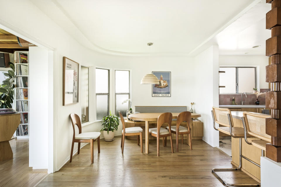 A dining area with wooden mid-century style furniture and banquette seating