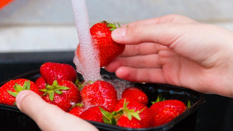 Strawberries being washed under running water. - Image: Nataly Mayak (Shutterstock)