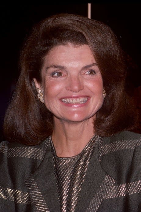 Jackie Kennedy Onassis and older man smiling at an event, man in a formal suit with bowtie