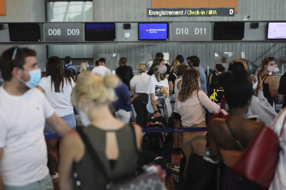 People queue in line to check-in for a British Airways flight to Heathrow airport, Friday Aug.14, 2020 at Nice airport, southern France. British holidaymakers in France were mulling whether to return home early Friday to avoid having to self-isolate for 14 days following the U.K. government's decision to reimpose quarantine restrictions on France amid a recent pick-up in coronavirus infections. (AP Photo/Daniel Cole)