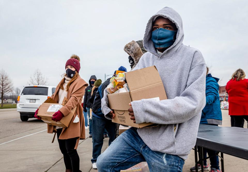 Djay Harris balances a box of food as he waits for the next car to pull up Dec. 18 in Jacksonville, Ill., as volunteers distribute food to anyone in need for the Central Illinois Foodbank.