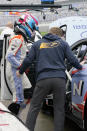 Robert Wickens, left, with the help of physical trainer Jim Leo climbs in his car during practice for the Rolex 24 hour auto race at Daytona International Speedway, Thursday, Jan. 27, 2022, in Daytona Beach, Fla. (AP Photo/John Raoux)