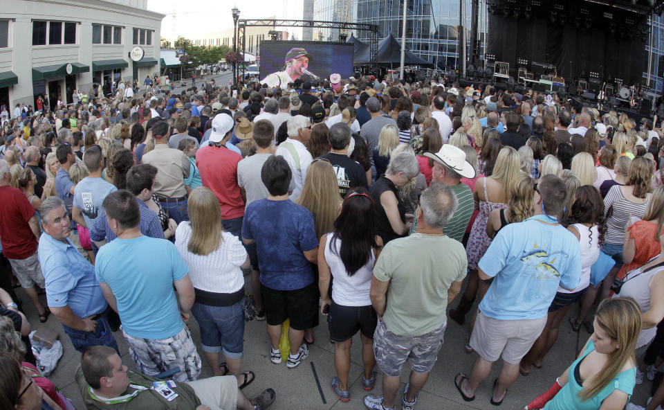 Country music fans watch Luke Bryan's performance on a giant screen as the CMT Music Awards show is shown outside Bridgestone Arena on Wednesday, June 6, 2012, in Nashville, Tenn. (AP Photo/Mark Humphrey)